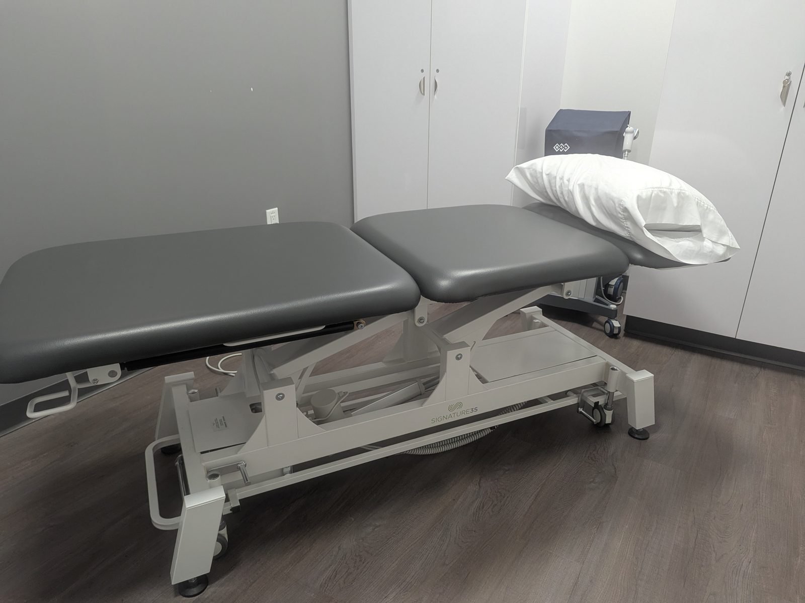 A treatment room with a powered plinth made up with a pillow