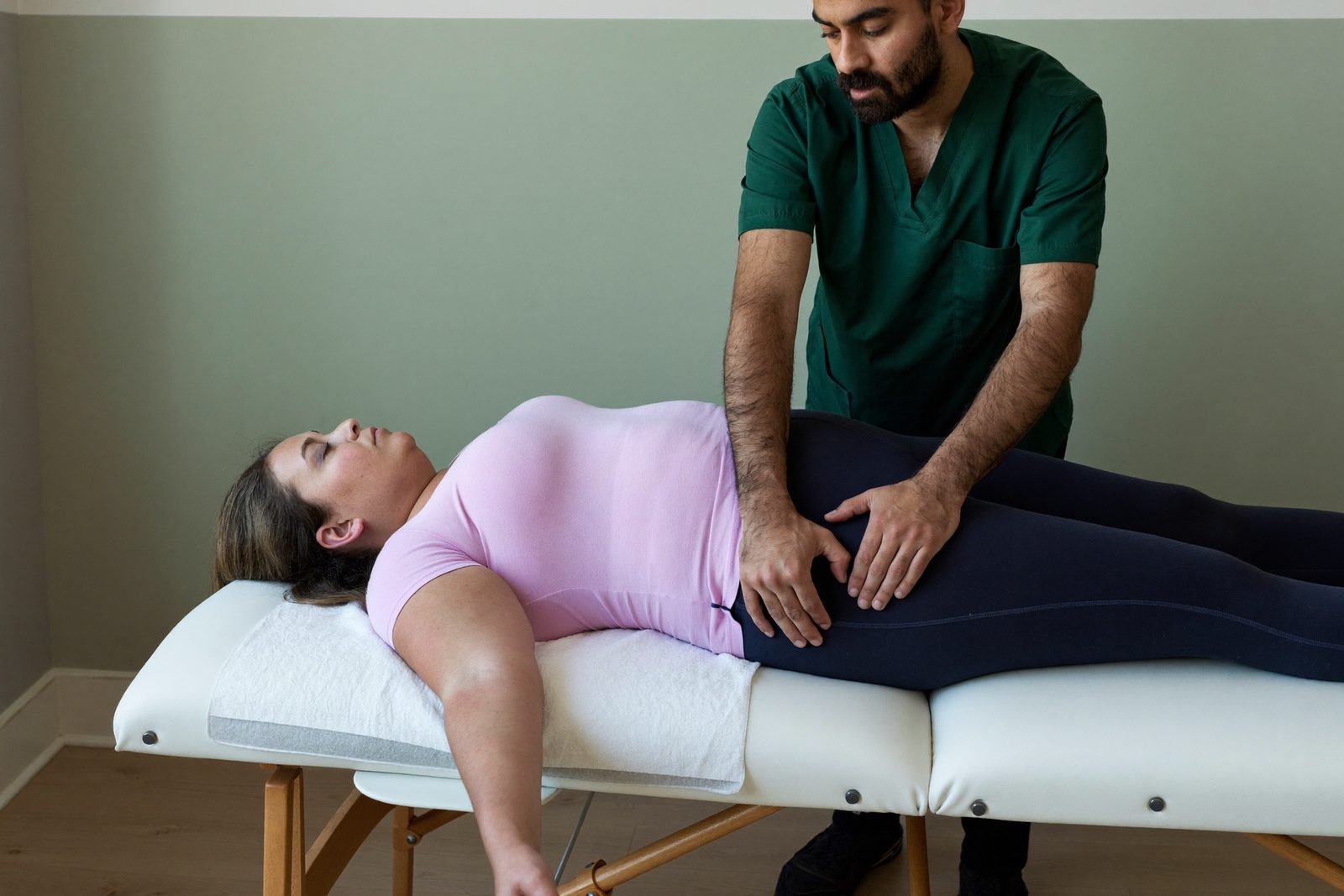 Slow, light drainage strokes along a patient's hip and thigh, with barely any pressure