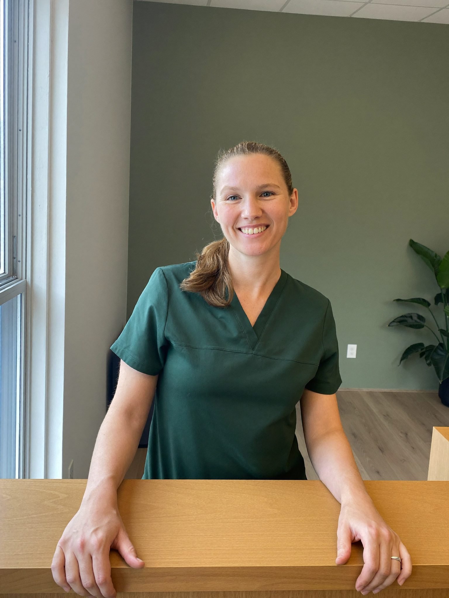 A member of the clinic team at reception, looking up to greet someone arriving