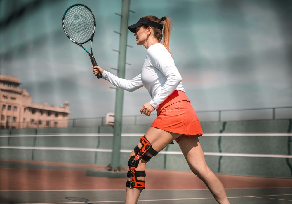 A woman playing tennis wearing a hinged brace on one knee