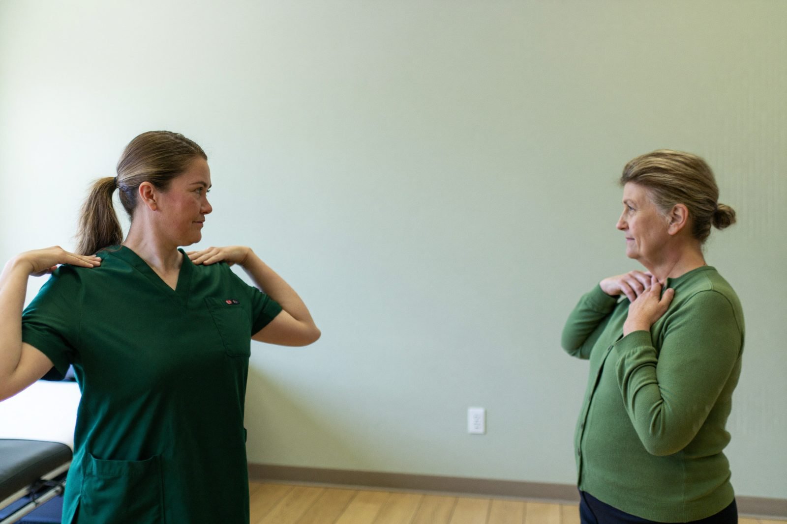 A physiotherapist and patient working through a shoulder movement side by side
